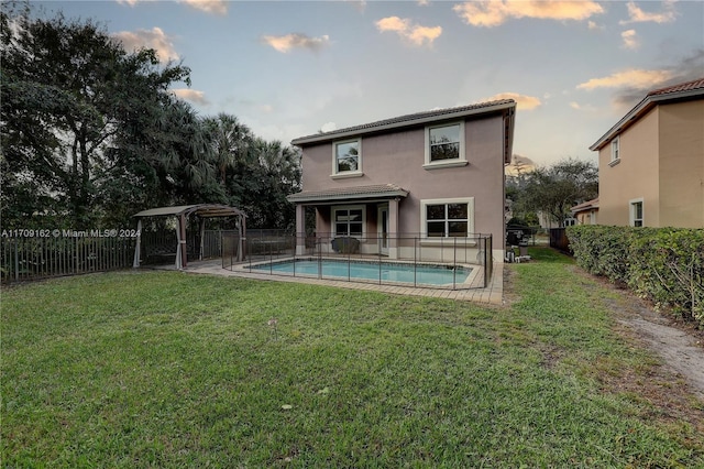 back of property with a fenced in pool and a yard