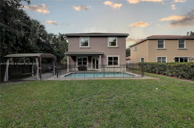 pool at dusk featuring a lawn and a patio