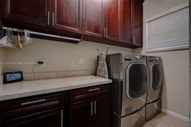 laundry area featuring washer and clothes dryer, cabinets, and light tile patterned floors