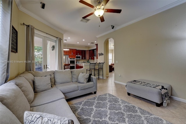 tiled living room with ceiling fan and crown molding