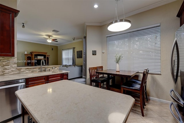 kitchen featuring ornamental molding, stainless steel appliances, ceiling fan, sink, and hanging light fixtures