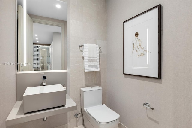 bathroom with sink, tile walls, and toilet