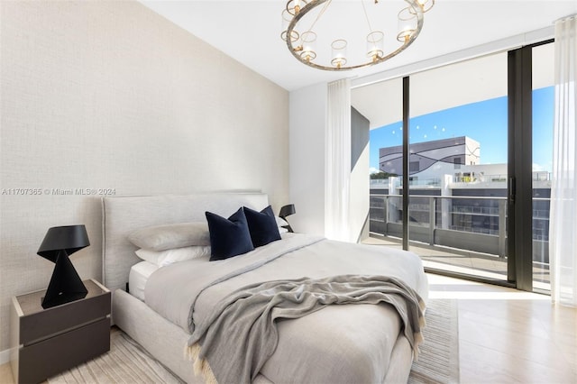 bedroom with access to exterior, a wall of windows, and a chandelier