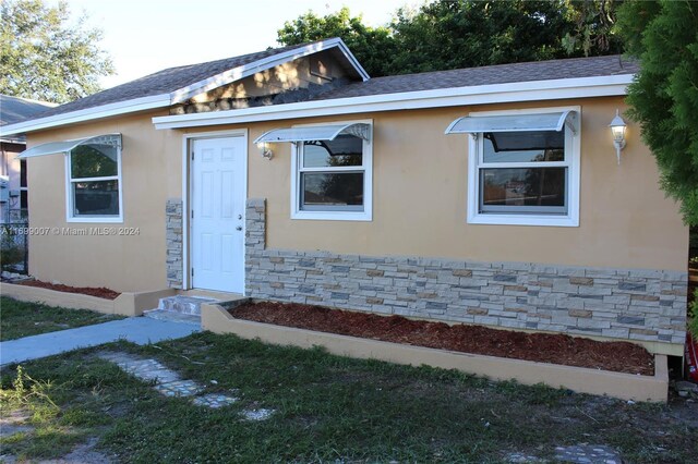 1918 NW 82nd St, Miami, FL 33147 - bungalow-style house with stucco siding, stone siding, and a shingled roof