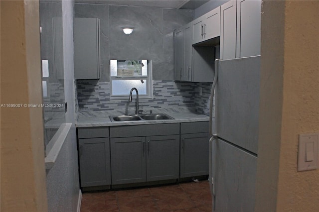 kitchen with refrigerator, backsplash, gray cabinetry, and sink