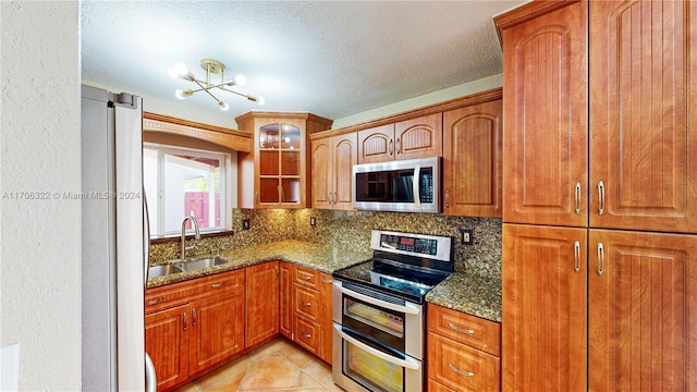 kitchen featuring dark stone countertops, sink, appliances with stainless steel finishes, and tasteful backsplash