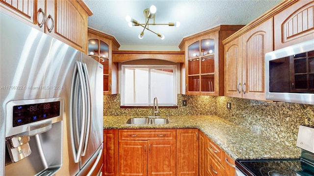 kitchen with sink, stainless steel appliances, tasteful backsplash, a chandelier, and stone countertops