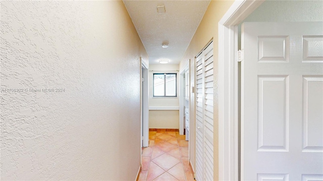 corridor featuring light tile patterned floors and a textured ceiling