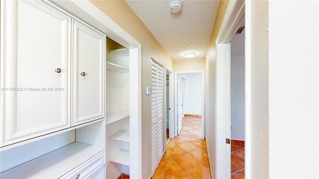 corridor featuring light tile patterned floors and a textured ceiling