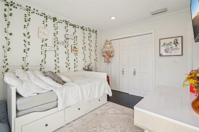 bedroom with hardwood / wood-style floors, a closet, and ornamental molding