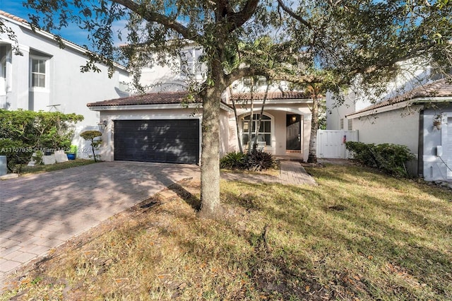 mediterranean / spanish-style house with a garage and a front lawn