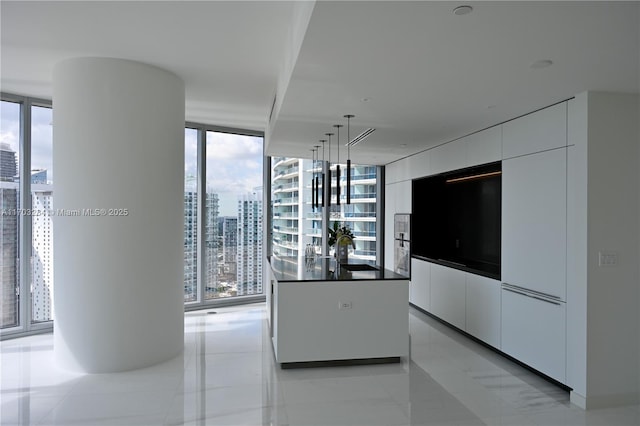 kitchen featuring hanging light fixtures, white cabinetry, a healthy amount of sunlight, and expansive windows