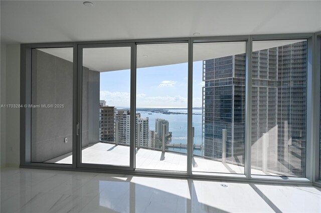 empty room featuring a water view, a wealth of natural light, and floor to ceiling windows