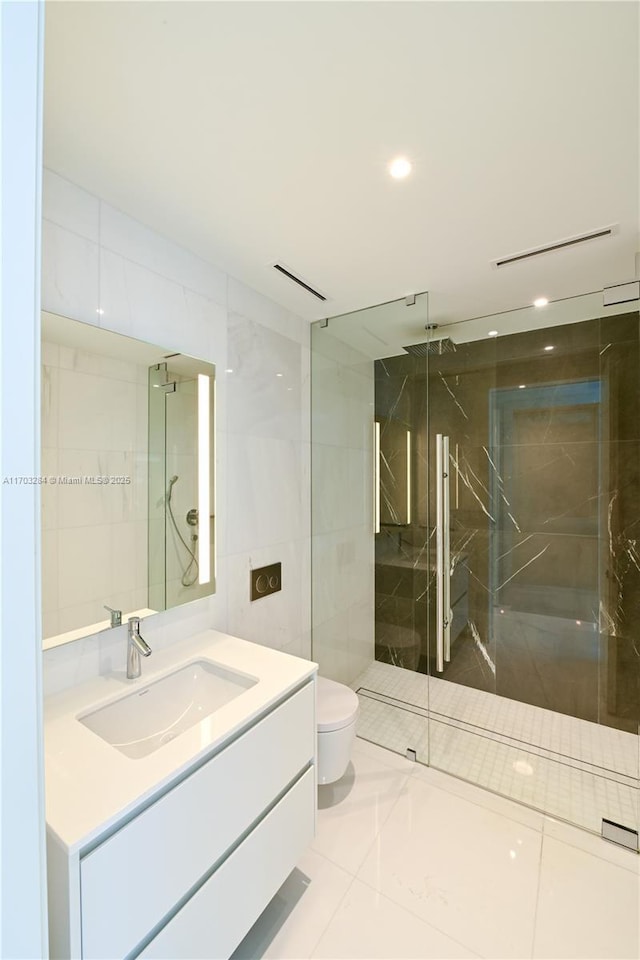 bathroom with tile patterned floors, vanity, tile walls, toilet, and walk in shower