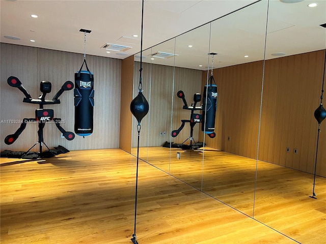 workout room with light hardwood / wood-style flooring and wooden walls