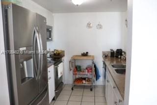 kitchen with stainless steel fridge, white cabinetry, and light tile patterned floors