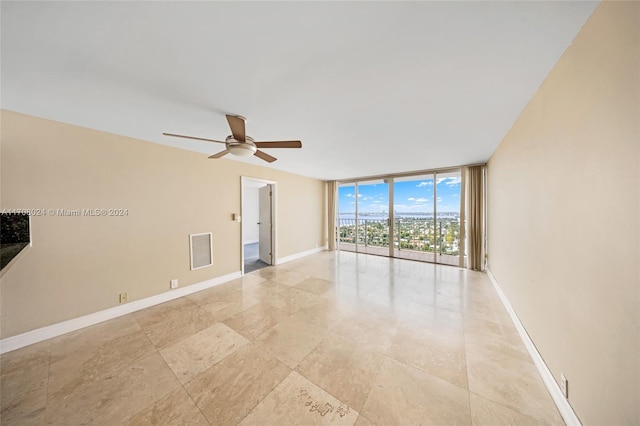 unfurnished room with ceiling fan and floor to ceiling windows