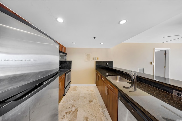 kitchen featuring sink, dark stone countertops, and stainless steel appliances