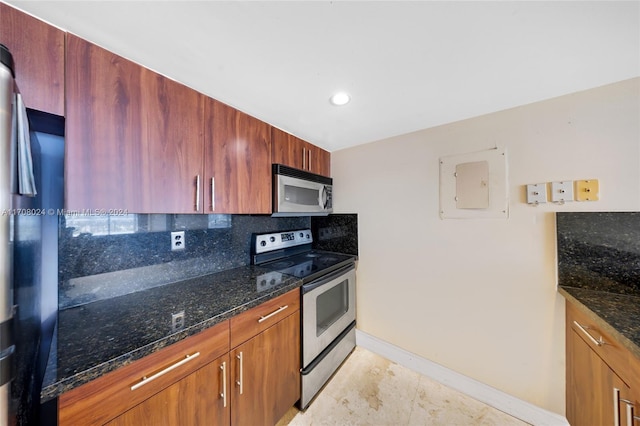 kitchen featuring appliances with stainless steel finishes, backsplash, electric panel, and dark stone counters