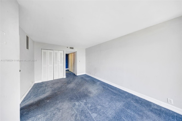 unfurnished bedroom with dark colored carpet and a closet