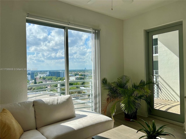 living area featuring a ceiling fan, a city view, a healthy amount of sunlight, and wood finished floors