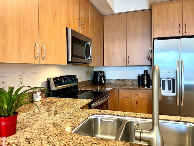 kitchen with brown cabinets, light stone countertops, and appliances with stainless steel finishes