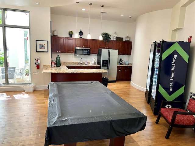 kitchen featuring a peninsula, appliances with stainless steel finishes, a healthy amount of sunlight, and light wood-style flooring