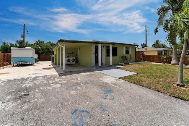 back of property with a lawn, a carport, and independent washer and dryer