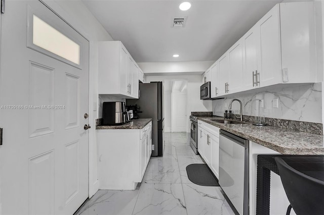 kitchen with tasteful backsplash, dark stone counters, stainless steel appliances, sink, and white cabinets