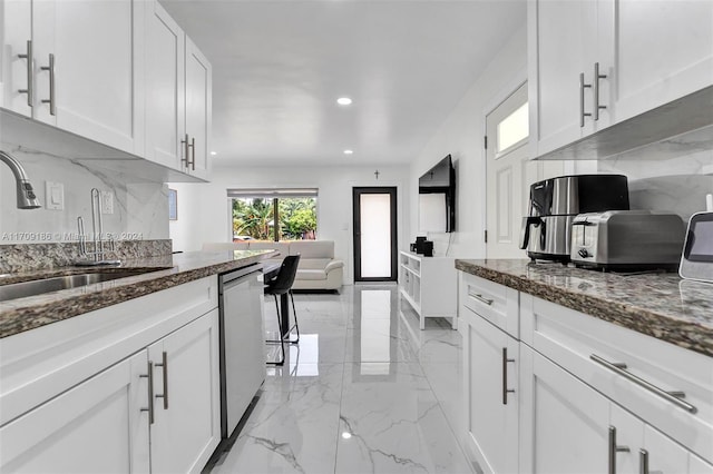 kitchen featuring backsplash, white cabinets, sink, stainless steel dishwasher, and stone countertops