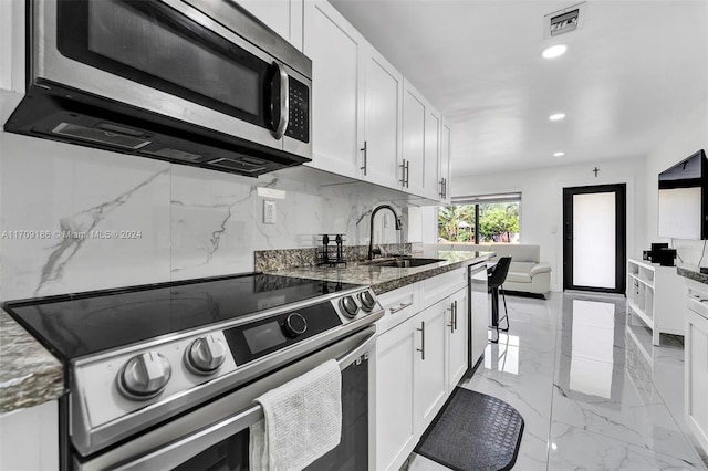 kitchen featuring dark stone countertops, sink, white cabinetry, and stainless steel appliances