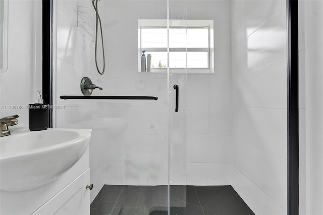 bathroom featuring a shower with door and vanity