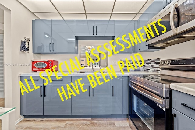 421 NE 14th Ave Unit 405, Hallandale Beach, FL 33009 - kitchen with stainless steel appliances, light countertops, a sink, light wood-style flooring, and a drop ceiling