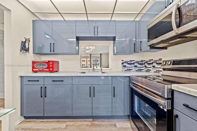 kitchen with sink, an inviting chandelier, light hardwood / wood-style flooring, decorative backsplash, and appliances with stainless steel finishes