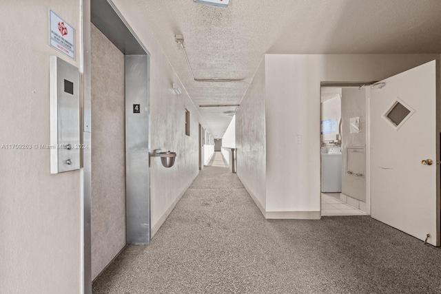 hallway with washer / dryer, a textured ceiling, and elevator