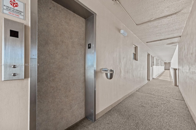 hallway featuring carpet, a textured ceiling, and elevator