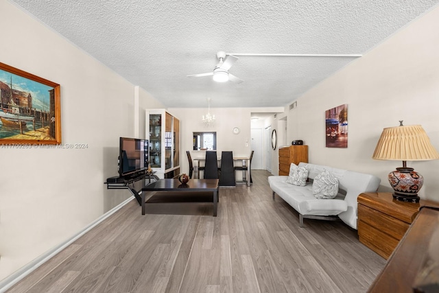 living room featuring a textured ceiling, ceiling fan with notable chandelier, and light hardwood / wood-style floors