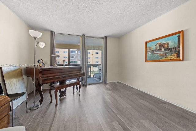 miscellaneous room with wood-type flooring, a textured ceiling, and floor to ceiling windows