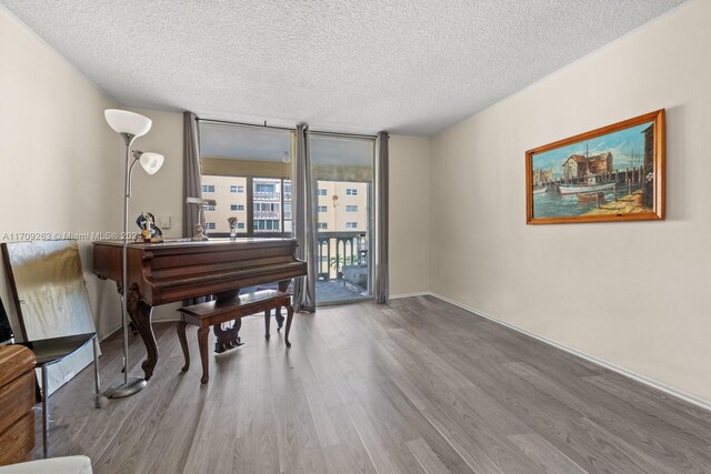 421 NE 14th Ave Unit 405, Hallandale Beach, FL 33009 - living area featuring wood finished floors, a textured ceiling, a wall of windows, and baseboards