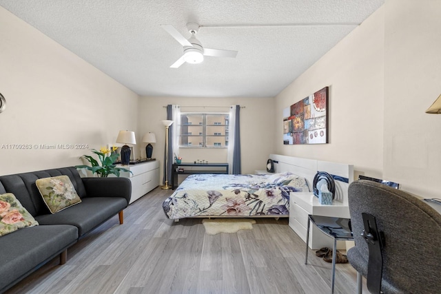 bedroom featuring ceiling fan, light hardwood / wood-style floors, and a textured ceiling