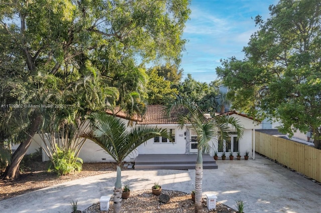 mediterranean / spanish-style house featuring concrete driveway, fence, and a tile roof