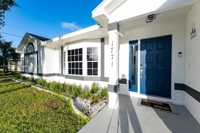 view of exterior entry featuring a lawn