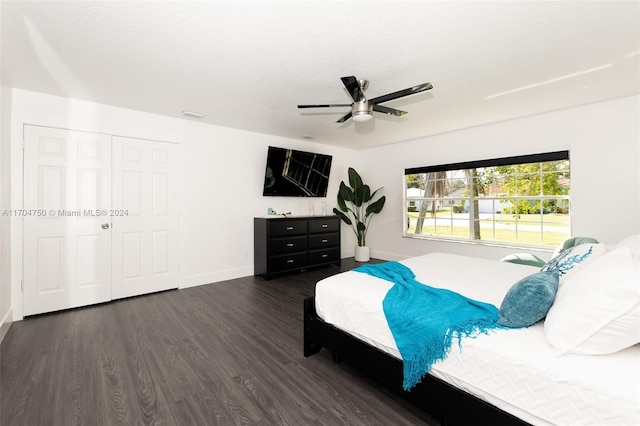 bedroom with a closet, ceiling fan, dark hardwood / wood-style flooring, and a textured ceiling