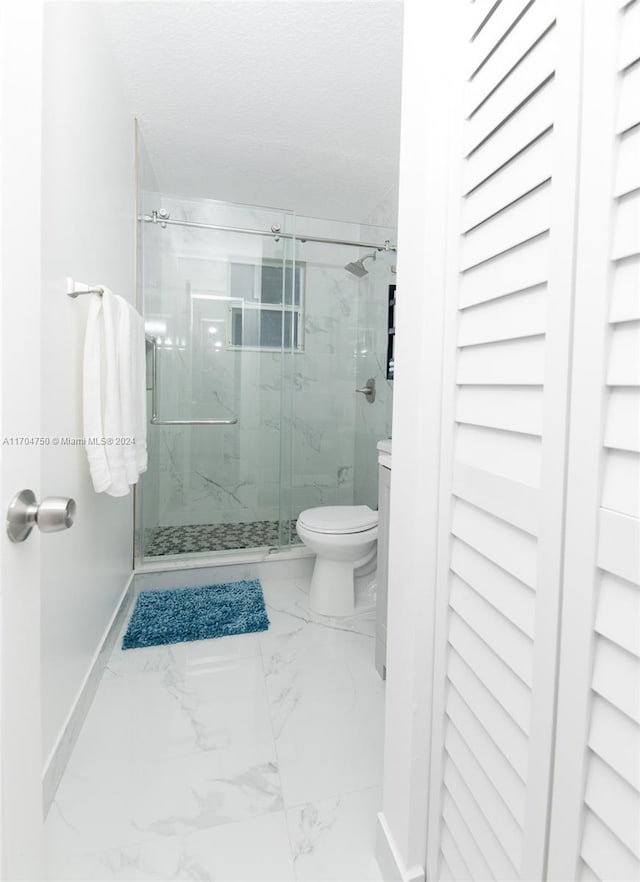 bathroom with a shower with door, a textured ceiling, and toilet