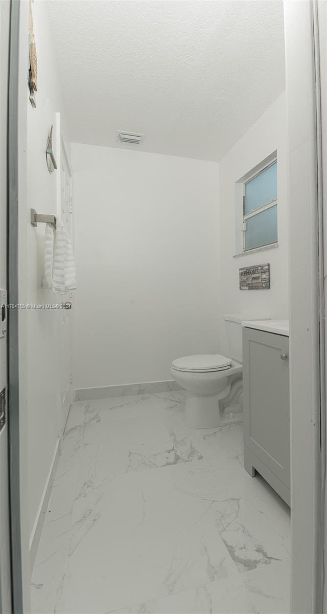 bathroom featuring vanity, a textured ceiling, and toilet