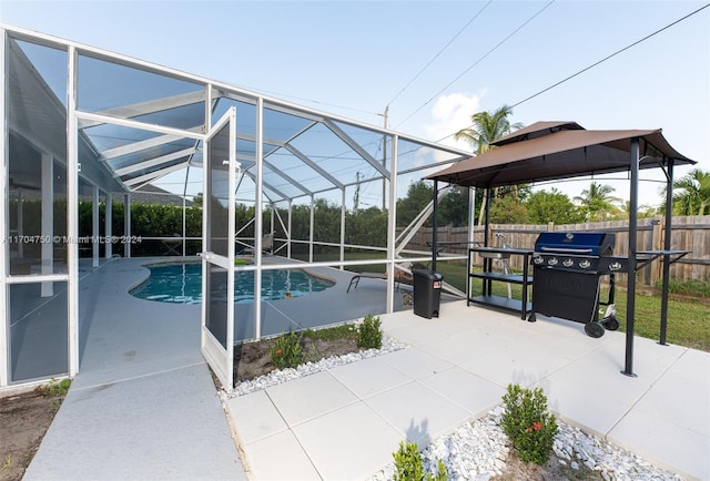 view of pool with glass enclosure, area for grilling, and a patio