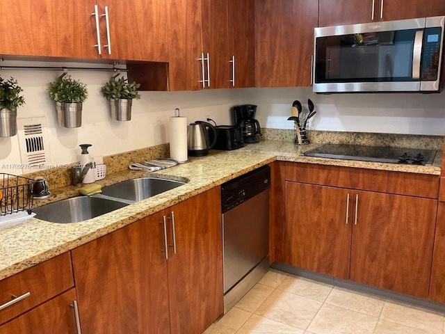 kitchen with light stone countertops, appliances with stainless steel finishes, light tile patterned floors, and sink