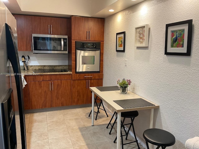 kitchen featuring light tile patterned floors, stainless steel appliances, and dark stone countertops