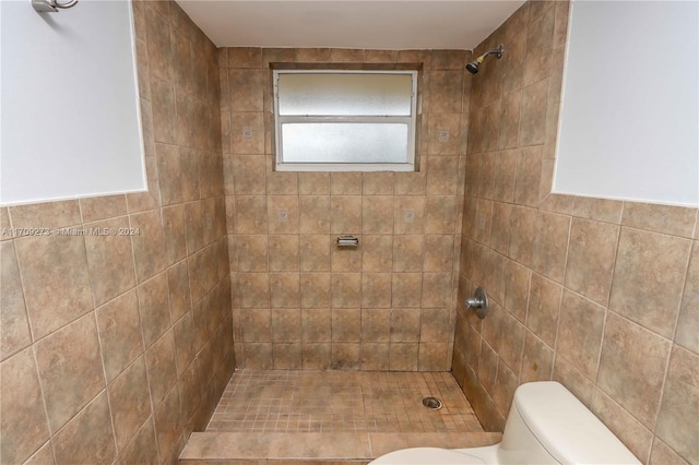 bathroom featuring tiled shower, toilet, and tile walls