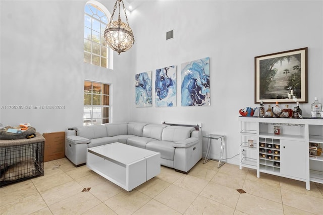 tiled living room featuring a towering ceiling and a notable chandelier